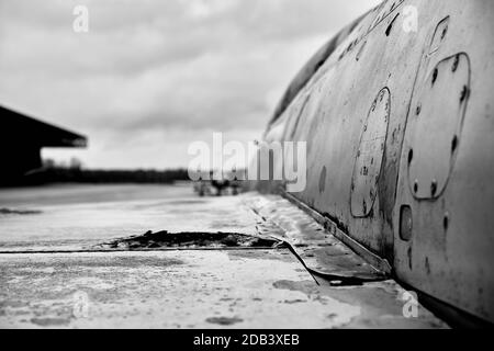Cliché en niveaux de gris d'un avion abandonné rouillé sous un ciel nuageux avec arrière-plan flou Banque D'Images