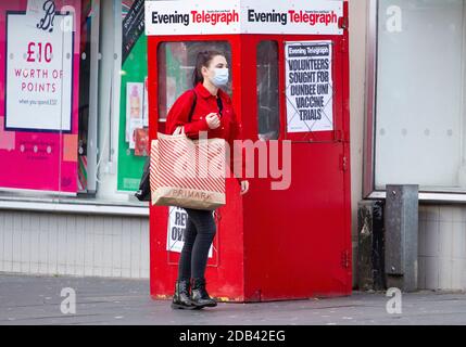 Dundee, Tayside, Écosse, Royaume-Uni. 16 novembre 2020. UK News Covid-19 Lockdown. Les personnes qui marchent dans les rues de Dundee avec peu de magasins de vêtements essentiels ouverts depuis que la restriction plus stricte de niveau 3 Covid-19 Lockdown a été appliquée. Une femme à la mode est consciente des directives de distanciation sociale et du port de masques de marche tout en tenant un grand sac de transport en papier Primark pendant ses achats de début de Noël dans le centre-ville, dans un après-midi froid et ensoleillé de novembre. Crédit : Dundee Photographics/Alamy Live News Banque D'Images