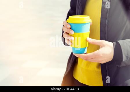 Les mains des femmes tiennent le mug à café réutilisable à l'extérieur. Emportez votre café partout avec votre tasse de voyage réutilisable. Aucun gaspillage. Concept de mode de vie durable. Banque D'Images
