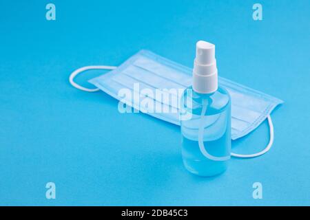 Gel désinfectant pour les mains et masque hygiénique jetable sur fond bleu avec espace pour les copies. Flacon de désinfectant pour les mains, vaporisateur de liquide antimicrobien, germe Banque D'Images