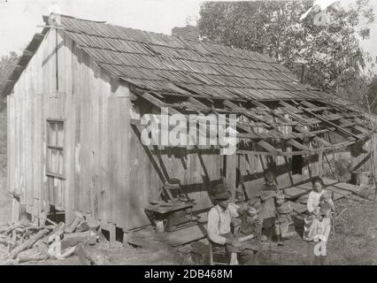 Frank Burditt et sa famille. Ils louent cette cabane délabrée et tentent de vivre au large de la terre maigre à proximité. . Banque D'Images