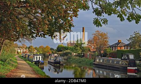 Le soleil de la fin de l'après-midi capture les couleurs de l'automne, un bateau de croisière étroit et l'ancienne cheminée du moulin à Burscough sur le canal de Leeds et Liverpool. Banque D'Images