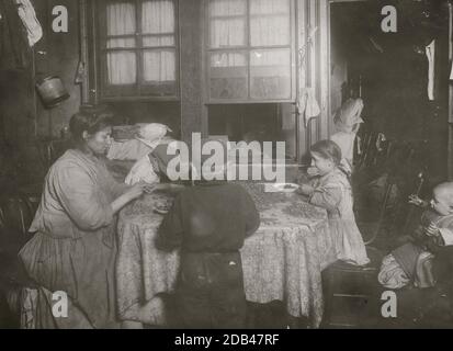 Mme Raphael Marengin, [...] St., au premier étage, à l'arrière. Pepine, 10 ans, craquer les noix avec ses dents. La mère venait de faire de même. La carmine, 8 ans, a des yeux croisés, et avec le garçon à peu près le même âge fonctionne aussi. Certains d'entre eux travaillent jusqu'à 8 ou 9 heures à certains moments. Garçon tenant bébé est stupide. Le mari travaille sur le chemin de fer une partie du temps. fille de 10 ans qui craque des noix avec ses dents. La mère venait de faire de même. l'enfant de 8 ans a des yeux croisés et des œuvres, ainsi que le garçon. New York, 1911. La fabrication de nourriture dans les maisons de location est maintenant interdite dans l'État de New York. Banque D'Images