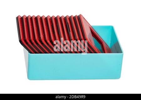 Gros plan d'une boîte en plastique turquoise avec des diapositives de film encadrées en rouge et noir isolées sur un fond blanc. Divertissement du siècle dernier pour regarder des vacances p Banque D'Images