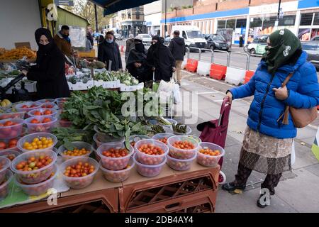 Alors que les Londoniens de la communauté principalement asiatique attendent le deuxième confinement national du coronavirus, c'est comme d'habitude au marché de Bethnal Green Road avec des gens qui sortent et s'en sortent, certains portant des masques et d'autres pas, Sur ce qui sera les quelques jours de la normalité avant un verrouillage total d'un mois au Royaume-Uni le 2 novembre 2020 à Londres, Royaume-Uni. Le système à trois niveaux au Royaume-Uni n'a pas fonctionné suffisamment pour supprimer le virus, et des politiciens ont reçu des appels pour qu'un verrouillage complet de « disjoncteur » soit annoncé pour aider à la propagation croissante du Covid-19. Banque D'Images