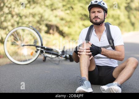 Le cycliste est tombé de vélo avec genou blessé Banque D'Images