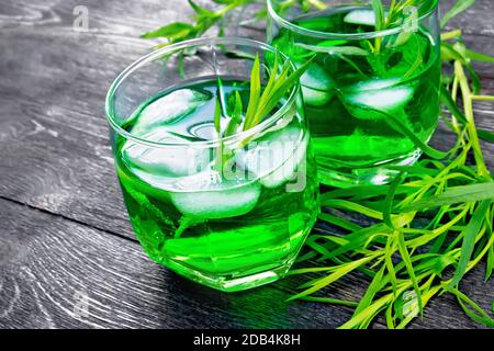 Limonade à l'estragon avec glace dans deux verres, brindilles à l'estragon sur fond de planche en bois Banque D'Images