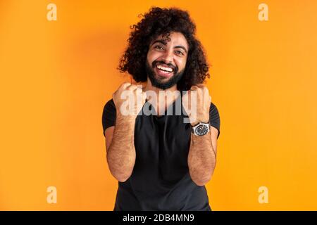 joyeux barbu fêtez son gagnant, sourire, briller le mec avec bonheur, concept de victoire. isolé fond orange Banque D'Images