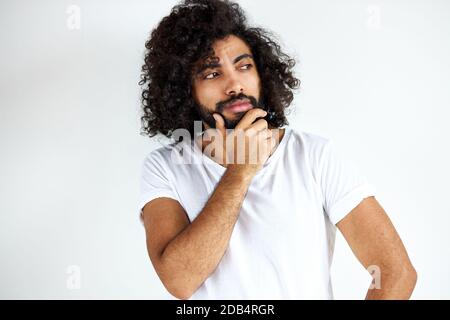 le mâle barbu est dans la contemplation, le gars beau en tenue décontractée regardant loin, isolé sur fond blanc Banque D'Images