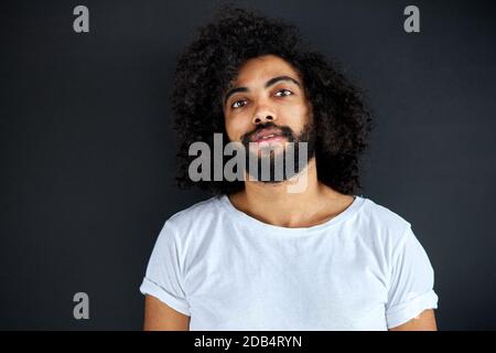 un homme arabe indien agréable en chemise regardant l'appareil photo, a un regard amical, un gars ouvert d'esprit isolé sur fond noir Banque D'Images