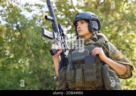 militaire courageuse et puissante, avec mitraillette à carabine debout dans la forêt, elle est prête à tirer à l'ennemi, tir à l'extérieur d'arme à feu Banque D'Images