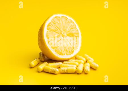 Capsules de vitamines. Pilules de vitamine C et citron jaune sur fond jaune. Banque D'Images