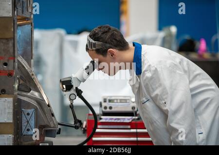 l'ingénieur vérifie le réglage correct du moule métallique pour les moulages en usine à l'aide d'un microscope. Banque D'Images