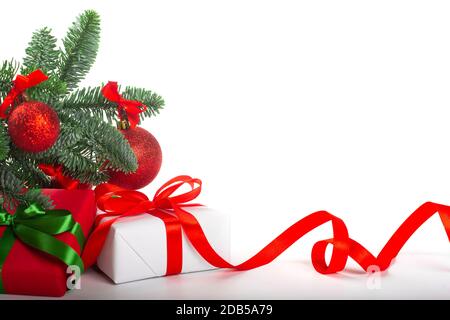 Blanc cadeau de vacances boîtes-cadeaux avec noeud rouge satiné et ruban bouclés sous arbre de Noël avec boules, cadre de bordure isolé sur fond blanc Banque D'Images