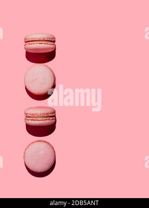 Macarons roses avec espace de copie. Rangée de macarons ou macarons français parfaits sur fond rose. Vue de dessus ou plat. Lumière dure Banque D'Images