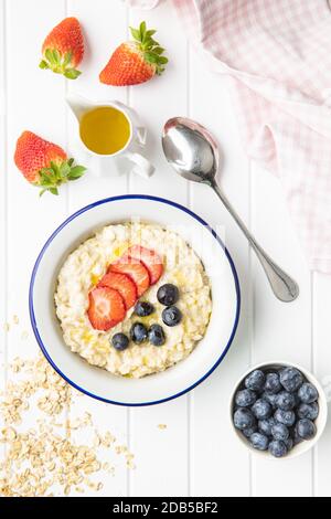 Bol de porridge de flocons d'avoine avec fraises et bleuets. Vue de dessus. Banque D'Images