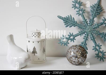 Décoration de Noël : flocon de neige bleu à paillettes artificielles, porte-bougie et porte-bougie en porcelaine blanc, figurine, bullfinch oiseau sur la console. Copier l'espace Banque D'Images