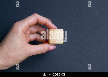 La main contient 1 cube sur fond noir, avec un siège pour le texte. Banque D'Images