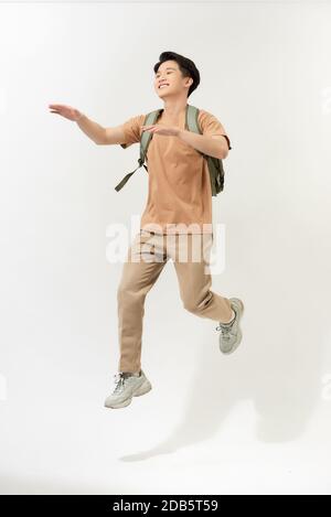 joyeux jeune homme souriant avec sac à dos sautant dans l'air arrière-plan blanc Banque D'Images