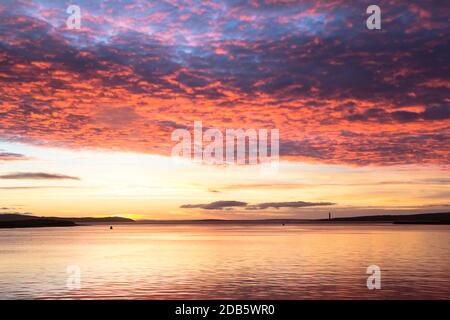 Nuages multicolores au-dessus de la mer du Nord calme dans la ville d'Orkney pendant lever du soleil Banque D'Images