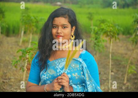 Gros plan d'une jeune fille bengali indienne portant un sari bleu avec de longs poils foncés et des bijoux dorés comme des boucles d'oreilles de collier, focalisation sélective Banque D'Images