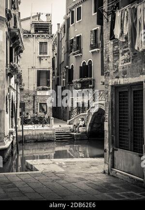 Un couple se trouve sur un pas à Rio Tera sant' Aponala, une petite rue calme à Venise, en Italie Banque D'Images