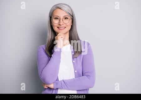 Photo portrait d'une femme intelligente et aînée dans le l'université porte des lunettes souriantes face à contact isolée sur la couleur grise Banque D'Images