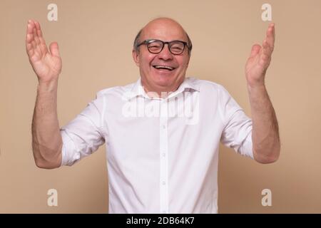 Homme hispanique senior en lunettes riant sur blague. Banque D'Images