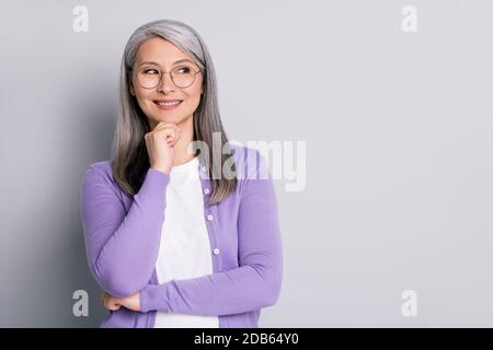Photo portrait d'une femme d'affaires intelligente et aînée qui porte des lunettes regarder côté penser à l'idée touchant visage souriant isolé en gris Banque D'Images