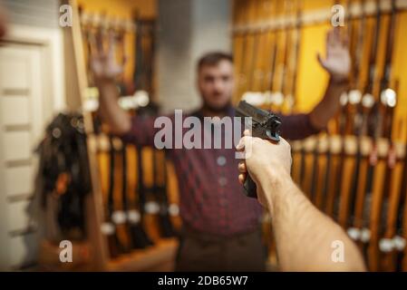 L'homme vise avec une nouvelle arme de poing sur le vendeur dans la boutique d'armes à feu. Homme personne achetant pistolet pour la sécurité dans magasin d'armes, autodéfense et le sport de tir hobby Banque D'Images