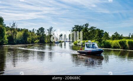 Le bateau gonflable à moteur flotte sur une rivière, entouré de roseaux et de tentatives, belle journée d'été sur la marina de bateaux de Szczecin, Pologne Banque D'Images