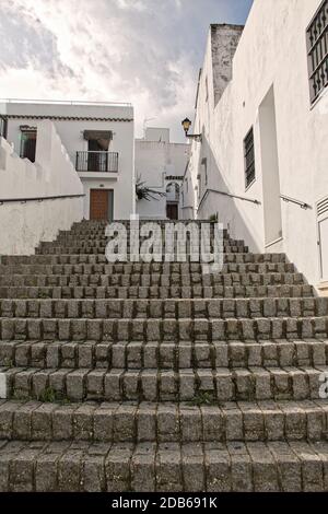 Rue raide typique avec des escaliers en pierre pavée à Vejer de la Frontera, une ville touristique dans la province de Cadix, Andalousie, sud de l'Espagne. Banque D'Images