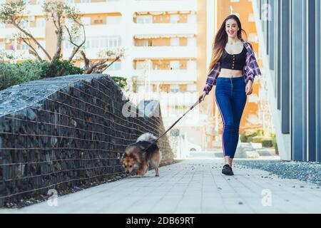 Femme marchant chien dans la rue de la ville Banque D'Images