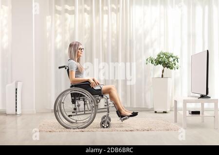 Photo d'une jeune femme blonde en fauteuil roulant regarder la télévision Banque D'Images