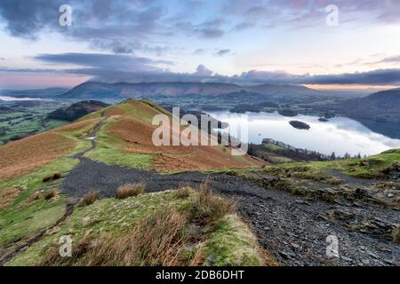 Sentier public menant à la montagne Cat Bells et au lac Derwentwater à droite de l'image. Couleurs subtiles de l'aube dans les nuages dans le ciel du matin. Banque D'Images