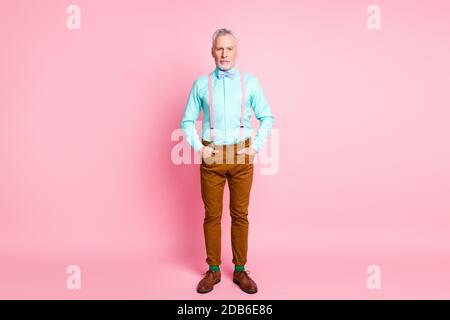 Portrait sur toute la longueur de la taille du corps d'un homme portant une tenue colorée noeud papillon debout mettre les mains dans les poches isolées sur la couleur rose arrière-plan Banque D'Images