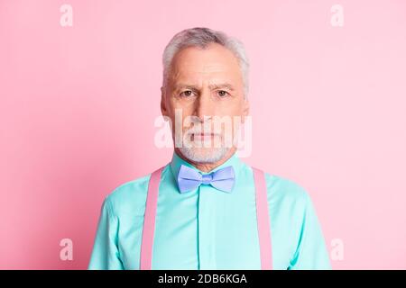 Photo portrait d'un homme âgé sérieux et confiant portant une chemise sarcelle noeud papillon et bretelles isolés sur fond rose Banque D'Images