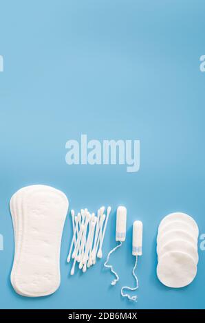 Accessoires d'hygiène féminine. Concept d'hygiène féminine pendant la menstruation. Tampon sanitaire, tampons, bourgeons de coton et tampons de coton sur fond bleu. Banque D'Images