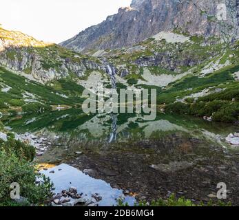 Lac de Velicke pleso avec chute de vodopad de Velicky sur Velicka dolina vallée dans les montagnes Vysoke Tatry en Slovaquie pendant la matinée d'automne avec ciel dégagé Banque D'Images