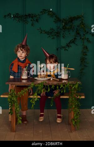 Les jeunes enfants jouent et fêtent leur anniversaire avec des petits gâteaux, du miel et des cocktails lors d'une fête à la maison. Concept de décoration élégante non typique Banque D'Images