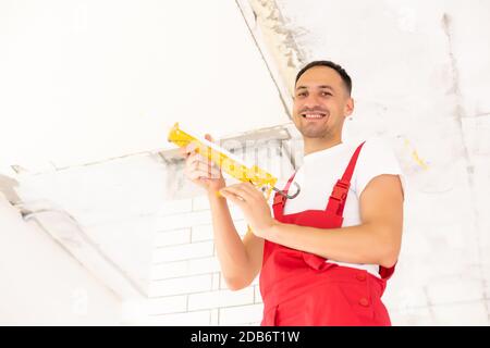 Jeune homme fixant au plafond isolé. Rénovation, construction Banque D'Images