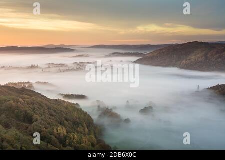 Magnifique brume persistante le matin de l'automne dans le Lake District, Royaume-Uni avec une couleur orange vive dans le ciel. Banque D'Images