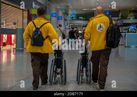 transport des personnes handicapées en fauteuil roulant à l'aéroport par le service d'assistance. Banque D'Images