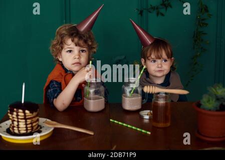 Les jeunes enfants jouent et fêtent leur anniversaire avec des petits gâteaux, du miel et des cocktails lors d'une fête à la maison. Concept de décoration élégante non typique Banque D'Images