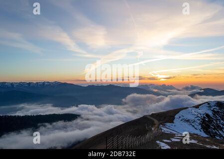 Haute montagne enneigée à travers les nuages dans le ciel bleu Banque D'Images