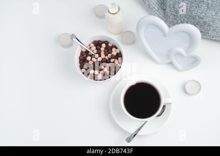 Boules de céréales aboules de chocolat et de céréales, une tasse de café et une bouteille de lait sur le fond d'un cadre avec des coeurs et des bougies.et une tasse de Banque D'Images