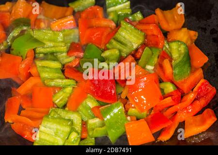 Poivrons coupés en rouge et vert dans un wok chinois Banque D'Images