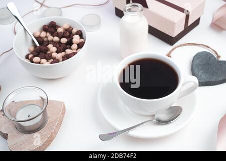 Une tasse de café et une assiette de boulettes de blé sur un fond festif avec des coeurs et un cadeau sur un fond clair. Banque D'Images