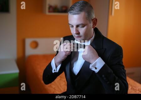 Gros plan d'un homme dans une chemise blanche, un costume noir et un noeud papillon. Mains de l'homme. Séance photo du marié. Photos de mariage. Dans les mains de l'homme d'affaires Bow t Banque D'Images
