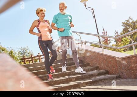 Plus sain et plus heureux. Prise de vue en longueur d'un couple de jeunes adultes actifs dans des vêtements de sport, qui se fera un plaisir de courir ensemble lors d'une chaude journée ensoleillée. Joyeux Banque D'Images